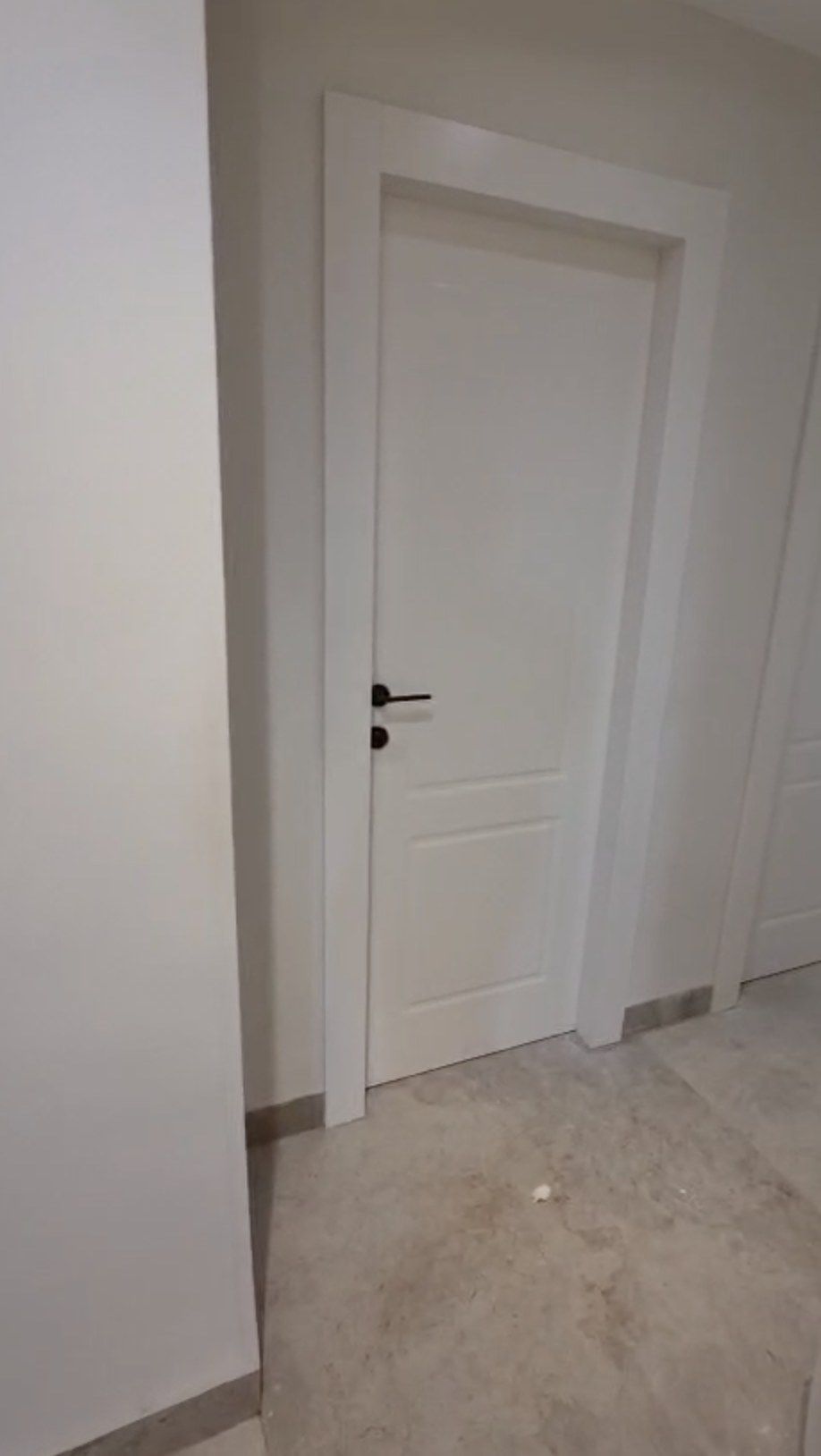 White panelled interior door with a black handle in a hallway