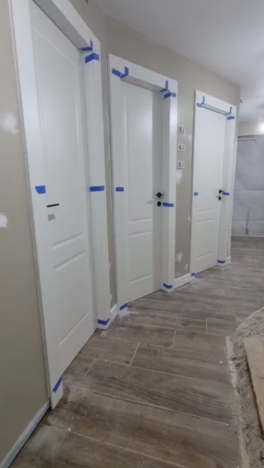 דלתות פנים לבנות בשלבי התקנה, המשקופים מוגנים בסרט הדבקה